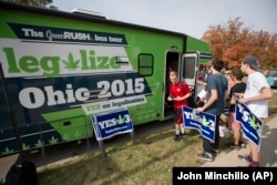 This October 23, 2015 file photo shows college students collecting lawn signs and shirts at a promotional tour bus from ResponsibleOhio, a pro-marijuana legalization group, at Miami University, in Oxford, Ohio.