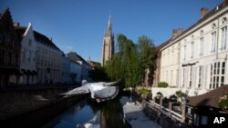 Dos palomas vuelan a través de un canal en Brujas, Bélgica, durante un levantamiento parcial de un bloqueo para prevenir la propagación del coronavirus, COVID-19.