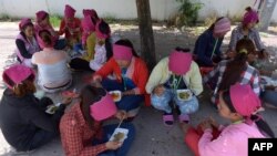 រូបឯកសារ៖ កម្មករ​រោងចក្រ​កាត់​ដេរ​សម្លៀកបំពាក់​កម្ពុជា​កំពុង​ទទួល​ទាន​អាហារ​ពេល​ថ្ងៃ​ត្រង់​នៅ​ក្រោម​ដើម​ឈើ​មួយ​ដើម នៅ​ខាង​មុខ​រោងចក្រ​ដែល​ពួកគេ​ធ្វើការ ភ្នំពេញ ថ្ងៃទី៨ ខែឧសភា ឆ្នាំ២០១៤។