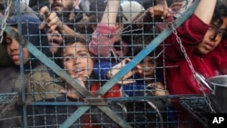 Palestinians line up to receive meals at Jabaliya refugee camp in the Gaza Strip on March 18, 2024.