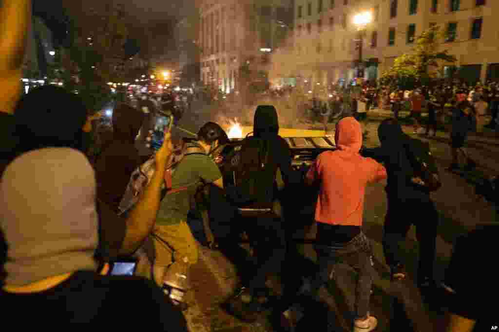 ក្រុមបាតុករ​រុញ​ធុង​សំរាម​ដែល​កំពុង​ឆេះ​ទៅ​កាន់​ប៉ូលិស​ក្នុងអំឡុងពេល​តវ៉ា​អំពី​ការស្លាប់​របស់​លោក George Floyd នៅ​ថ្ងៃសៅរ៍​ទី ៣០ ខែឧសភា ឆ្នាំ ២០២០ ក្បែរ​សេតវិមាន​ក្នុង​រដ្ឋធានី​វ៉ាស៊ីនតោន។ លោក Floyd បាន​ស្លាប់ បន្ទាប់ពី​ត្រូវបាន​ឃាត់ខ្លួន​ដោយ​ប៉ូលិស​នៅ​ទីក្រុង Minneapolis រដ្ឋមីនីសូតា សហរដ្ឋ​អាមេរិក កាលពី​ថ្ងៃចន្ទ ទី ២៥ ខែឧសភា ឆ្នាំ២០២០។ (AP) 