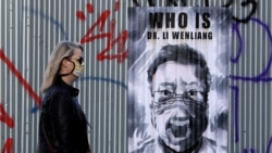 一名領導人口罩的捷克女子走過布拉格街頭一幅中國眼科醫生李文亮的遺像。（2020年3月27日）