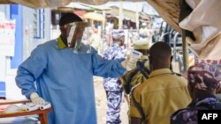 A medical assistant checks the temperature of people from Democratic Republic of Congo (DRC) at the Ebola screening point bordering with DRC in Mpondwe, western Uganda, on Dec. 12, 2018.