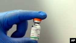 A medical worker poses with a vial of Sinopharm's COVID-19 vaccine in Belgrade, Serbia, Tuesday, Jan. 19, 2021. Serbia is the first European country to receive the Chinese Sinopharm coronavirus vaccine for mass inoculation programmes. (AP Photo…