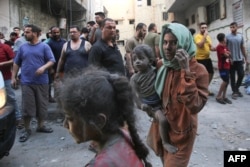 Una mujer palestina cubierta de polvo y tierra carga a un niño, mientras continúan las furiosas batallas entre Israel y el movimiento Hamas por sexto día consecutivo en la ciudad de Gaza, el 12 de octubre de 2023.