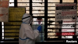 A medical worker gets ready to collect a sample from a man at a school turned into a center to conduct tests for the coronavirus disease (COVID-19), amidst its spread in New Delhi, India, June 22, 2020.