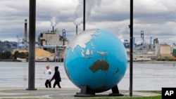 Transeúntes pasan frente a una escultura de la Tierra en el Theas's Park en Tacoma, Washington, en la costa oeste de EE.UU. el 21 de abril de 2020.