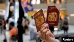 资料照：一名香港示威者在反对港版国安法的抗议中手举英国国民海外护照。（2020年6月1日）
