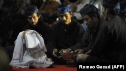 Suku Baduy berdoa di depan seikat padi yang baru dipanen saat upacara di istana Cigugur Pangeran Djati Kesuma, dihiasi dengan buah-buahan yang baru dipanen dalam upacara panen tahunan tradisional selama seminggu yang dikenal sebagai "Seren Taun" di Cigugu