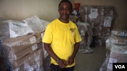 Andrew Raka, electoral officer in charge of Port Loko district, stands in front of some of the ballots which will be used during the election in Port Loko, Sierra Leone, March 10, 2018. (J. Patinkin/VOA)