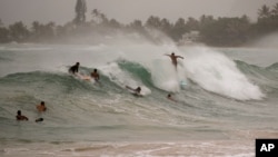 Surfistas enfrentan grandes olas generadas por el huracán Douglas en Laie Beach Park, en Laie, Hawái, el domingo, 26 de julio de 2020.