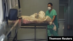 Un trabajador sanitario empuja una camilla con el cadáver de un fallecido por la COVID-19, en Tegucigalpa.