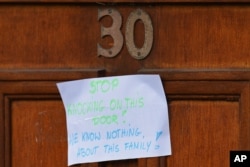 A sign on the front door of a house reads "Stop Knocking On This Door - We Know Nothing About This Family!!" is pictured on Elsmore Road in Fallowfield, Manchester, on May 24, 2017.