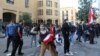 A Lebanese demonstrator hurls rocks over a fortified gate, leading to the Lebanese Parliament building, in downtown Beirut, March 13, 2021, during a protest against the political system.