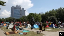 Pedestrians walk among tents set up by protesters in Gezi park, Taksim Square, Istanbul, June 6, 2013.