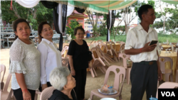 អ្នកស្រី ឡៅ ជាលីនដា (អាវស) ឈរស្វាគមន៍ភ្ញៀវមកចូលរួមបុណ្យសព លោក នួន ជា ជាឪពុក នៅវត្តព្រំគីរីមរកត ស្រុកសាលាក្រៅ ខេត្តប៉ៃលិន កាលពីថ្ងៃទី០៧ ខែសីហា ឆ្នាំ២០១៩។ (អូន ឆេងប៉រ/VOA)