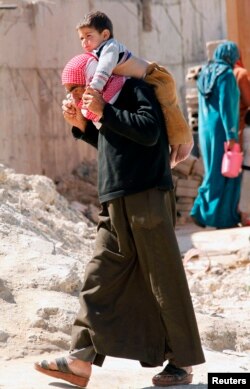 A Syrian refugee carries a child on his shoulders in Sidon, southern Lebanon Mar. 6, 2013.
