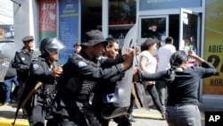 Policías antidisturbios desalojan a periodistas desde la entrada principal de su medio hasta una estación de policía en Mangua, Nicaragua, el 15 de diciembre del 2018
