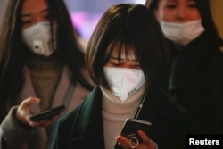Women wearing face masks wait for the bus in Langfang, Hebei province, China, Dec. 19, 2016.