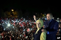 Turkey's President Recep Tayyip Erdogan and his wife Emine Erdogan pose for photos with cheering supporters in the background after unofficial referendum results were announced, in Istanbul, late Sunday, April 16, 2017.