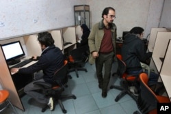 FILE- In this Tuesday, Jan. 18, 2011 file photo, Iranians work in an internet cafe in central Tehran, Iran. In Iran, a government push for a 'halal' internet means more control after protests. (AP Photo/Vahid Salemi, File)