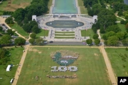 华盛顿国家大草坪上的芳草和绿树，人们用白色绿色和棕色的伞组成图案，庆祝国家公园系统建立100周年（2016年8月25日）