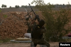 FILE - Syrian Democratic Forces fighters shoot at a drone they said belonged to Islamic State fighters on the bank of the Euphrates River, west of Raqqa city, Syria, April 8, 2017.