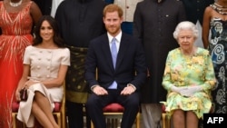 In this file photo taken on June 26, 2018 (L-R) Meghan, Duchess of Sussex, Britain's Prince Harry, Duke of Sussex and Britain's Queen Elizabeth II pose for a picture during the Queen's Young Leaders Awards Ceremony at Buckingham Palace in London. (Photo by John Stillwell / AFP)