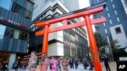 A group of foreign tourists wearing Japanese traditional kimono walk through a torii gate, the entrance of a shrine, in Nihonbashi shopping and office district in Tokyo, Nov. 19, 2014.