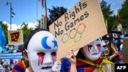 2021 年 6 月 23 日，西藏和維吾爾族活動人士在洛桑奧林匹克博物館前舉著標語牌並戴上口罩抗議，約有 200 名參與者參加了抗議活動。 （法新社）