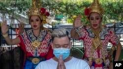  A man wearing a face mask pray at Erawan shrine as traditional dancers preform in Bangkok, Thailand, Wednesday, Jan. 29, 2020.