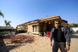 A policeman stands in front of a house hit by a rocket fired from Gaza Strip in Netivot, Israel, after it was hit by a rocket fired from Gaza Strip, Nov. 12, 2019.