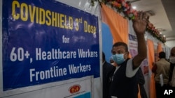 An Indian man waves to the camera before receiving his third dose of vaccination for COVID-19 at a government hospital in Gauhati, India, Jan. 10, 2022. 