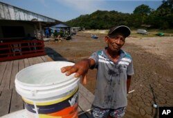 Raimundo Silva do Carmo, 67, shows the water he obtained from a well dug in the dry bed of Puraquequara Lake amid a severe drought, in Manaus, Amazonas state, Brazil, Thursday, Oct. 5, 2023. (AP Photo/Edmar Barros)