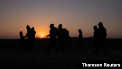 El sol sale mientras las familias de migrantes en busca de asilo de Honduras y El Salvador caminan hacia el muro fronterizo después de cruzar el río Grande hacia Estados Unidos, el 26 de marzo 2021.