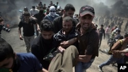 Waandamanaji wa Palestina wakiwa wamembeba mtu aliyejeruhiwa baada ya kupigwa na bunduki na majeshi ya Israeli, Jumatatu, Mei 14, 2018.