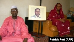 La femme de l'opposant disparu Ibni Oumar Mahamat Saleh, Sadia Brahim, à droite, et son cousin Moussa Mahamat Saleh posent devant le portrait du leader de l'opposition chez lui à N'Djamena, le 15 mai 2008.