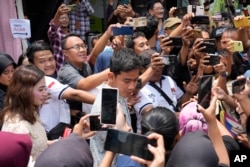 Calon wakil presiden yang juga putra sulung Presiden Jokowi, Gibran Rakabuming Raka, tengah, berbincang dengan pendukungnya usai mencoblos pada pemilu di TPS Solo, 14 Februari 2024. (Foto: AP)
