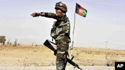 FILE - Afghan National Army soldier directs a vehicle to stop at a checkpoint on the way to Zhari district, where the Maiwand army base is located, in Kandahar, Afghanistan.