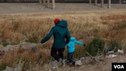 Un migrante guatemalteco y su hijo cruzan la frontera natural de Río Grande entre El Paso, estado de Texas, Estados Unidos, y Ciudad Juárez, estado de Chihuahua, México, en busca de asilo político el 26 de enero de 2021.