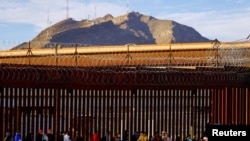 2023年1月5日，移民越過里約布拉沃河後，在美墨邊境圍欄附近排隊申請庇護。（路透社照片）