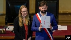 El presidente chileno, Gabriel Boric, sostiene el borrador final de la nueva Constitución, presentada por la presidenta del Consejo Constitucional, Breatriz Hevia, ante el consejo en el antiguo edificio del Congreso Nacional en Santiago, Chile, el 7 de noviembre de 2023.