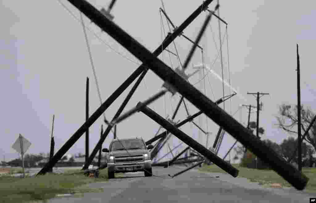 A driver works his way through a maze of fallen utility poles damaged in the wake of Hurricane Harvey, Aug. 26, 2017, in Taft, Texas.
