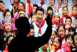 在北京展览馆前面，《砥砺奋进的五年》大型成就展的照片或绘画显示中国国家主席习近平戴着少先队的红领巾和少年儿童在一起，有参观者留下背影（2017年10月23日）