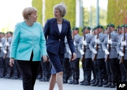 FILE - German Chancellor Angela Merkel, left, and British Prime Minister Theresa May walk on the red carpet during a military welcoming ceremony at the chancellery in Berlin, July 20, 2016.