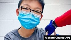 In this Dec. 22, 2020, photo, provided by Richard Chung, his son Caleb Chung receives the first dose of Pfizer coronavirus vaccine or placebo as a trial participant for kids ages 12-15, at Duke University Health System in Durham, N.C. (Richard Chung via AP)