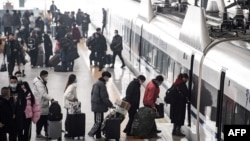 中國湖北漢口火車站的旅客在春節前的春運開始之際登上火車。 （2022年1月17日）