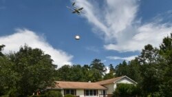 In this Tuesday, Aug, 7, 2018, photo a Wing Hummingbird drone from Project Wing arrives and sets down its package at the delivery location in Blacksburg, Va. (Michael Shroyer via AP)