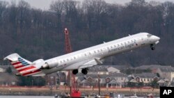 ARCHIVO - Mientras un avión de American Eagle despega, avanzan tareas de recuperación cerca del punto en el río Potomac donde cayeron los restos de un avión comercial y un helicóptero militar que chocaron en pleno vuelo, el 6 de febrero de 2025, en Arlington, Virginia. 