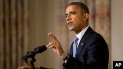 FILE - President Barack Obama gestures while making the second of three points while speaking in the State Dining Room of the White House.